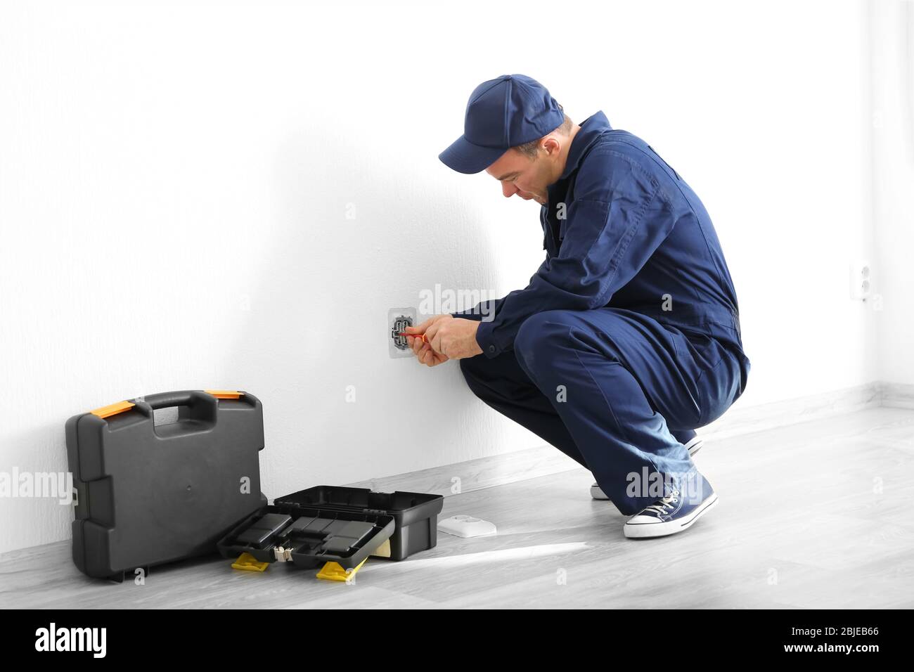 Electrician disassembling wall socket in new building Stock Photo