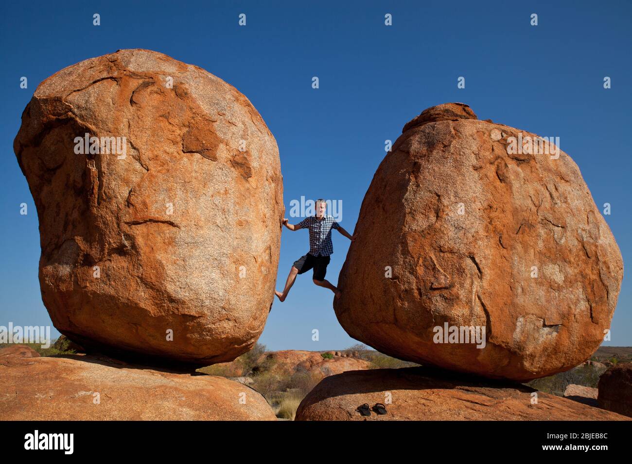 Man climbing the devils marbles Stock Photo
