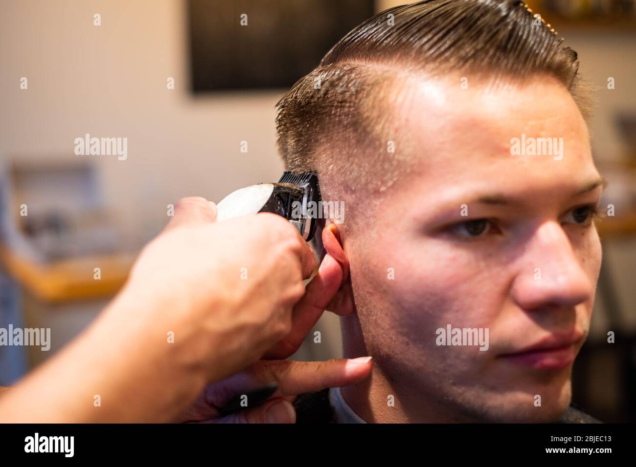Barber Sample Using Razor Barber trims the hair of a young man with a razor in his barbershop ...