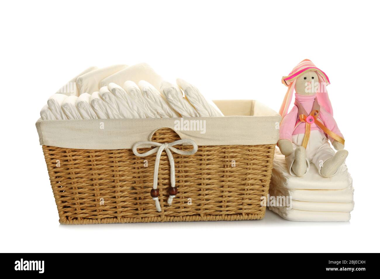 Baby diapers in wicker basket with toy, on white background Stock Photo