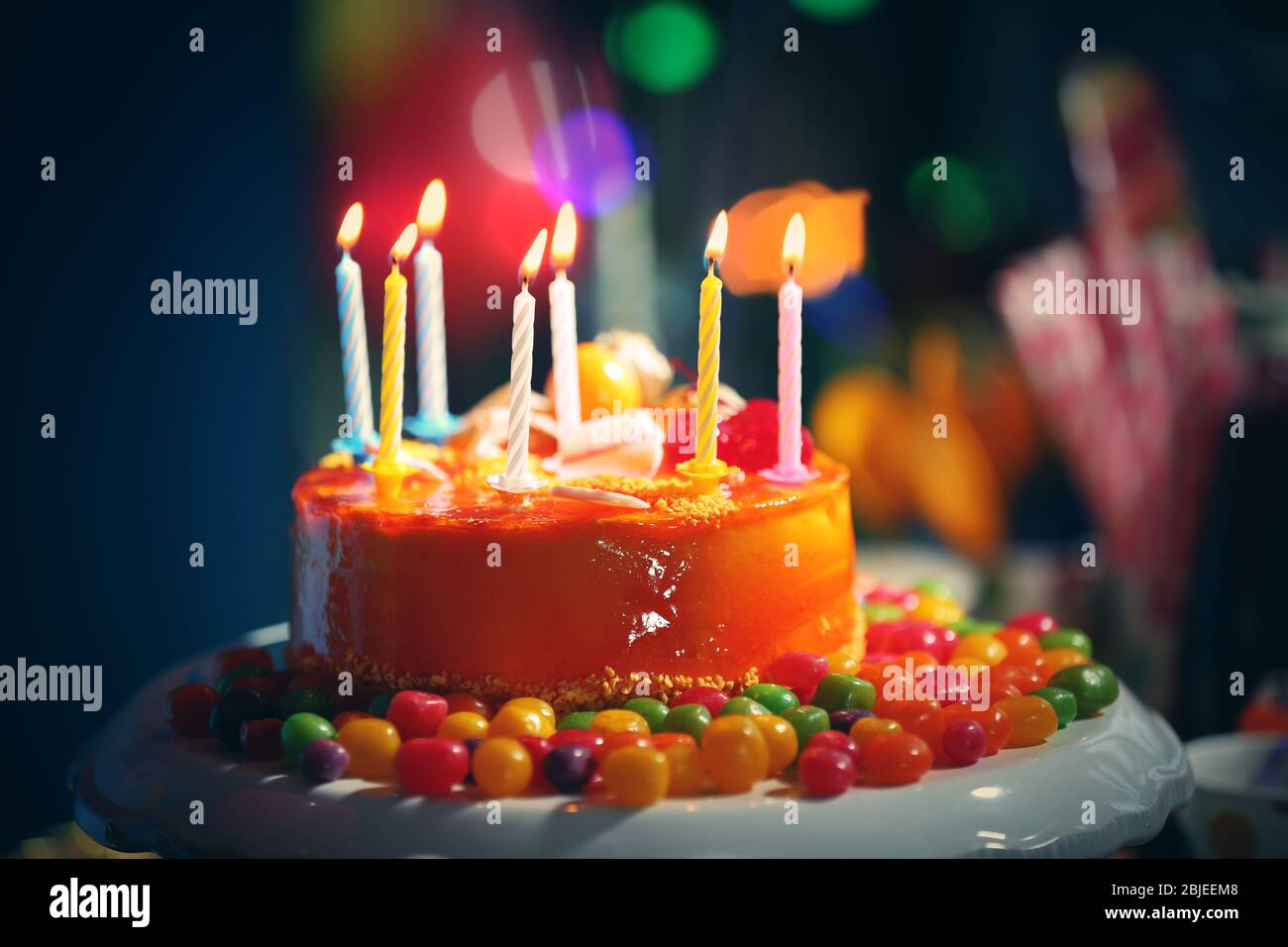 Tasty birthday cake with candles and sweets on blurred background Stock ...