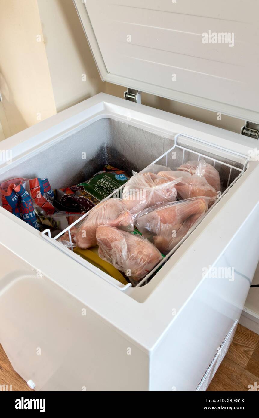 Open Upright Domestic Home Freezer Appliance Showing Contents Including Frozen Chicken Drumsticks Stock Photo