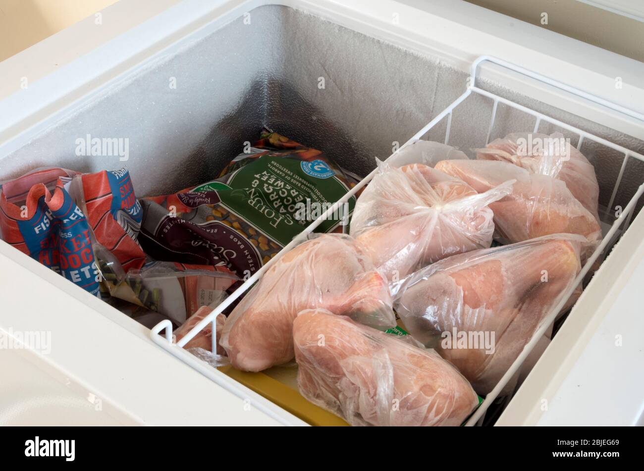 Open Upright Domestic Home Freezer Appliance Showing Contents Including Frozen Chicken Drumsticks Stock Photo