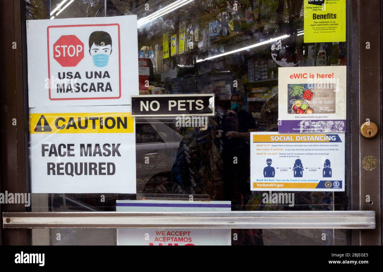 due to the coronavirus or covid-19 pandemic, a face mask is required to enter this store, as per these signs in English and Spanish on the door Stock Photo