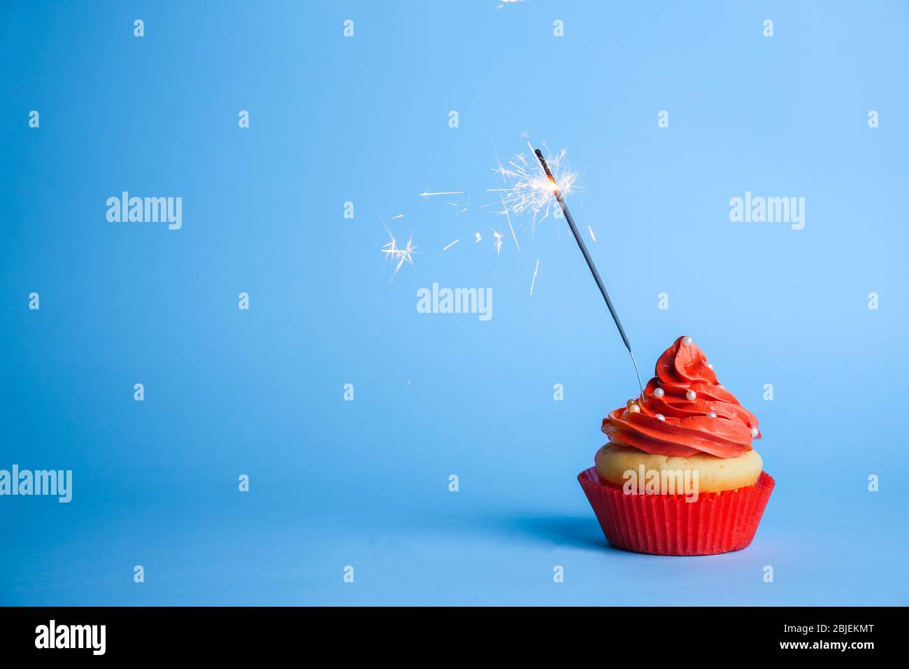 Cupcake with sparkler on color background Stock Photo - Alamy