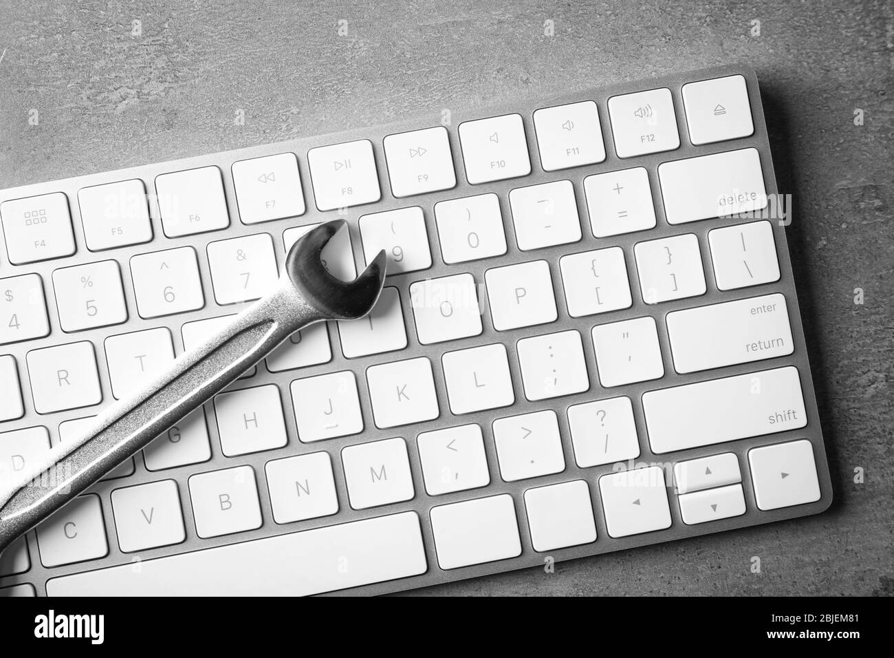Modern wireless keyboard and spanner on gray background Stock Photo
