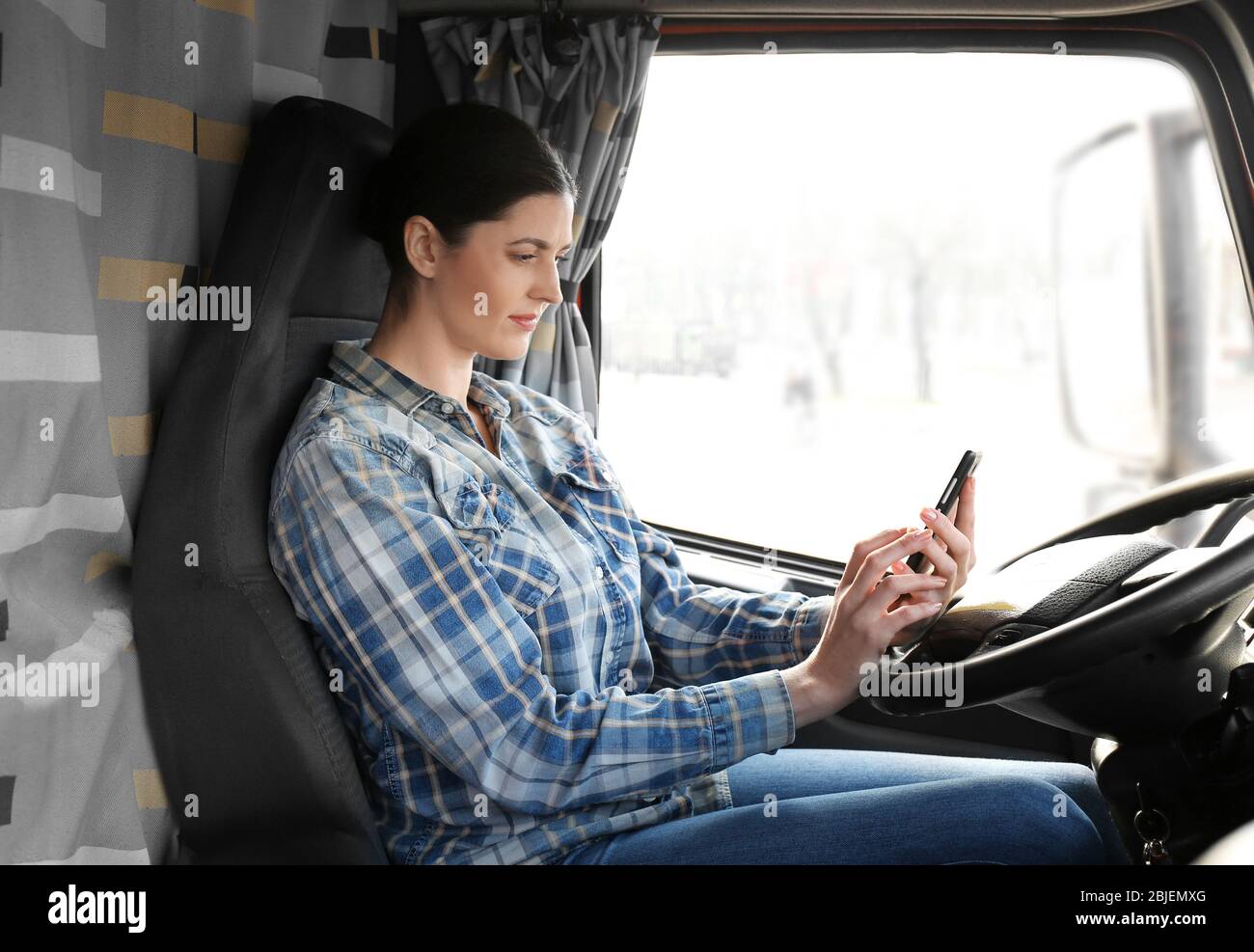 Young female driver sitting in cabin of big modern truck Stock Photo ...