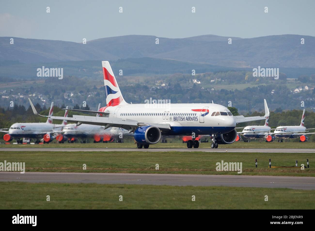 Glasgow, UK. 28 April 2020.   Pictured: A British Airways flight from London Heathrow arrives in Glasgow (with grounded Airbus BA jets in background), which is one of only a handful of scheduled flights into Glasgow today during the Coronavirus (COVID-19) crisis UK extended lockdown.  To date British Airways has made an announcement which sees almost 12,000 staff axed reacting to the pandemic which has hit every major airline, putting some out of business. Credit: Colin Fisher/Alamy Live News. Stock Photo