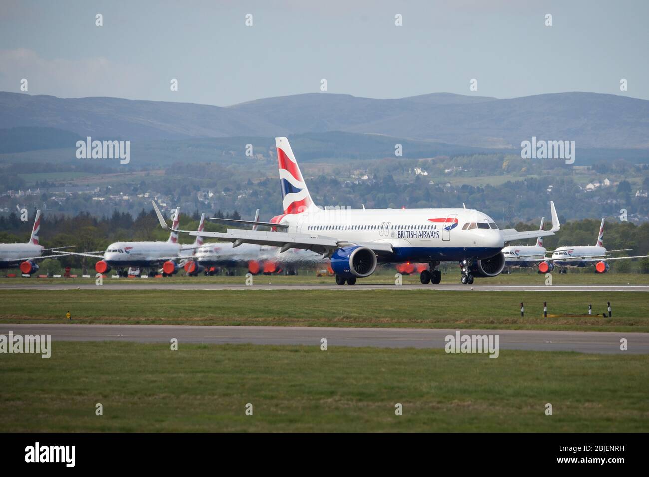 Glasgow, UK. 28 April 2020.   Pictured: A British Airways flight from London Heathrow arrives in Glasgow (with grounded Airbus BA jets in background), which is one of only a handful of scheduled flights into Glasgow today during the Coronavirus (COVID-19) crisis UK extended lockdown.  To date British Airways has made an announcement which sees almost 12,000 staff axed reacting to the pandemic which has hit every major airline, putting some out of business. Credit: Colin Fisher/Alamy Live News. Stock Photo