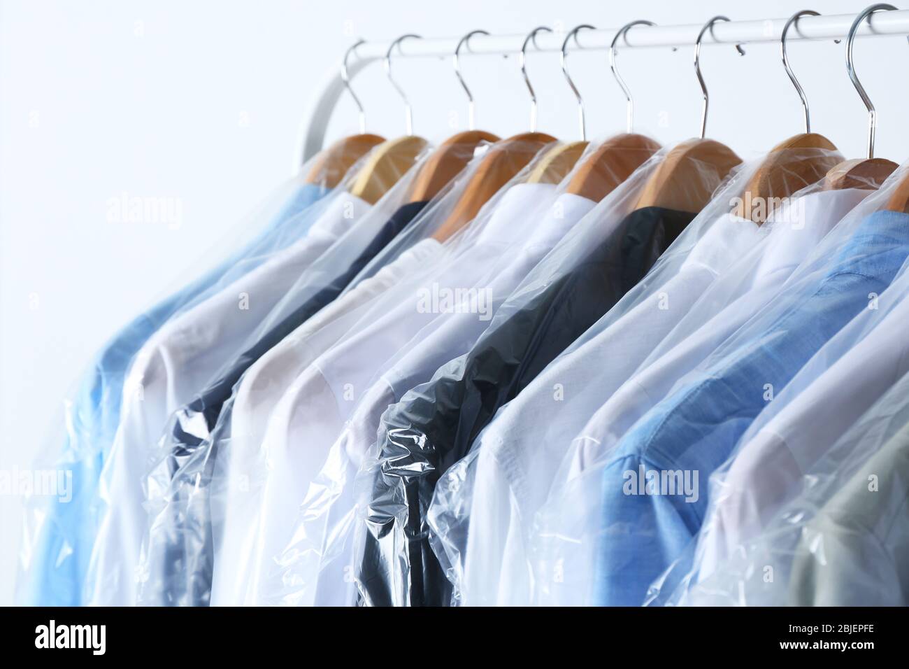 Rack of clean clothes hanging on hangers at dry-cleaning Stock Photo