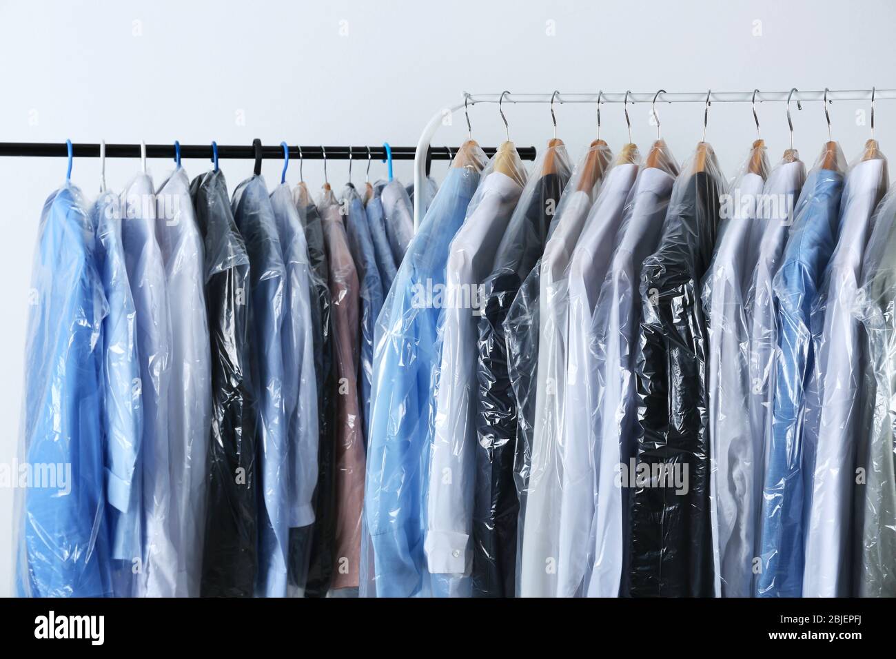 Rack of clean clothes hanging on hangers at dry-cleaning Stock Photo