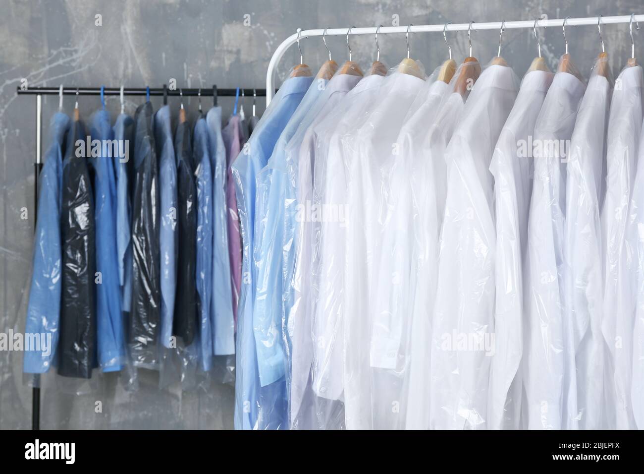 Rack of clean clothes hanging on hangers at dry-cleaning Stock Photo