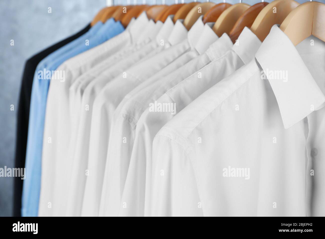 Rack of clean clothes hanging on hangers at drycleaning Stock Photo