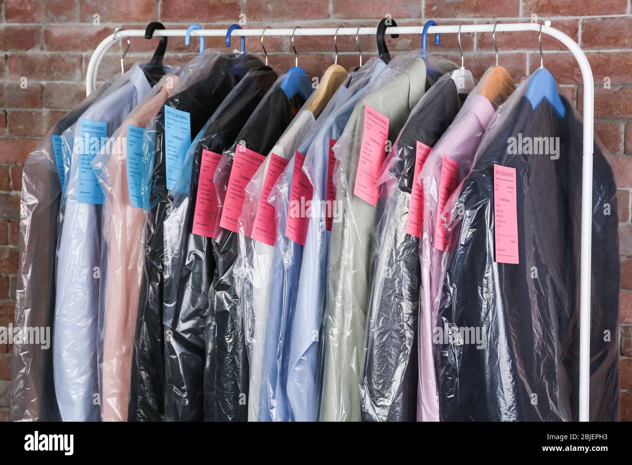 Rack of clean clothes hanging on hangers at dry-cleaning Stock Photo