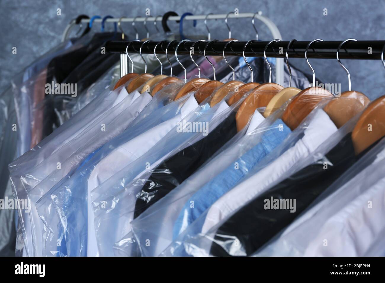 Rack of clean clothes hanging on hangers at drycleaning Stock Photo
