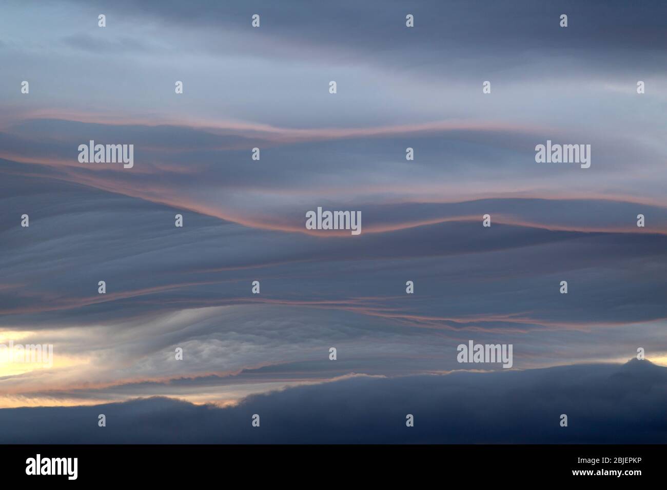 Brooding clouds catching a hint of the setting sun along their edge. Stock Photo