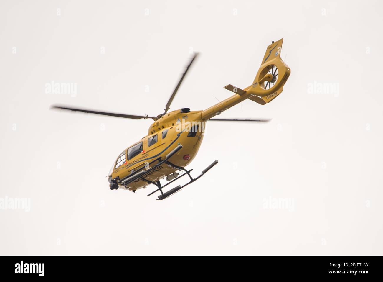Glasgow, UK. 28 April 2020.   Pictured: Scottish Air Ambulance Service helicopter (Airbus Helicopter H145 / EC145T2) seen about to land at the Queen Elizabeth University Hospital transferring more Covid-19 patients. Credit: Colin Fisher/Alamy Live News. Stock Photo