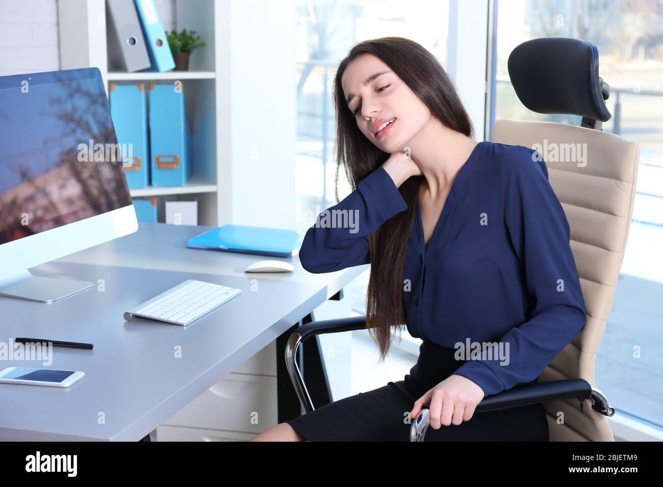 Posture concept. Young woman suffering from neck pain while working with computer at office