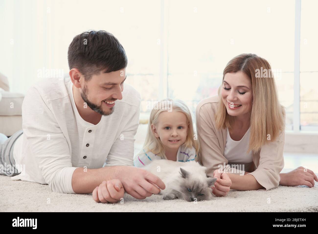 Mother, father and their daughter with cat at home Stock Photo - Alamy