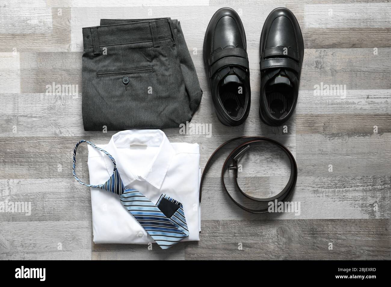 Clothes of schoolboy on wooden floor, flat lay Stock Photo