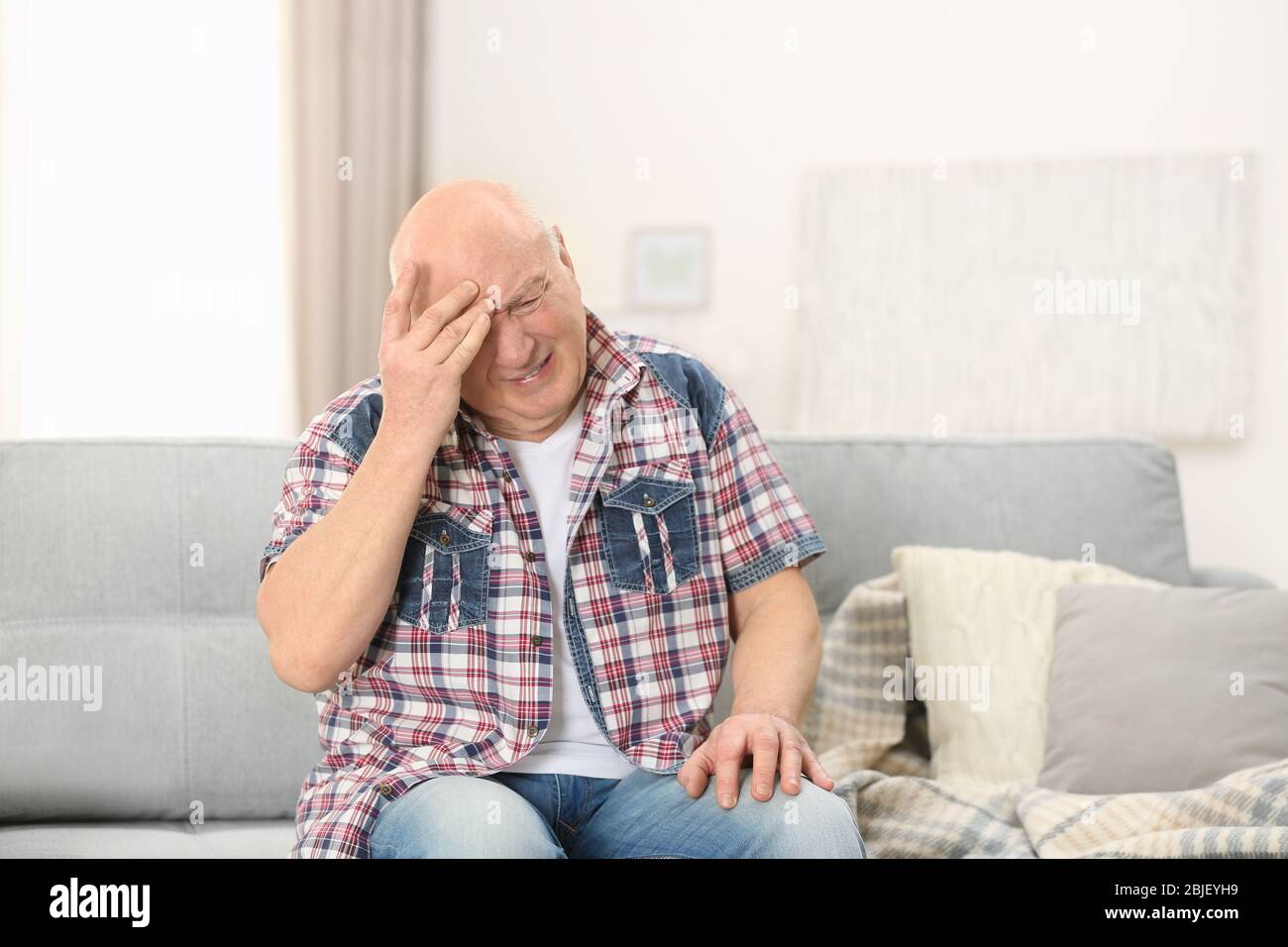 Senior man suffering from headache at home Stock Photo - Alamy