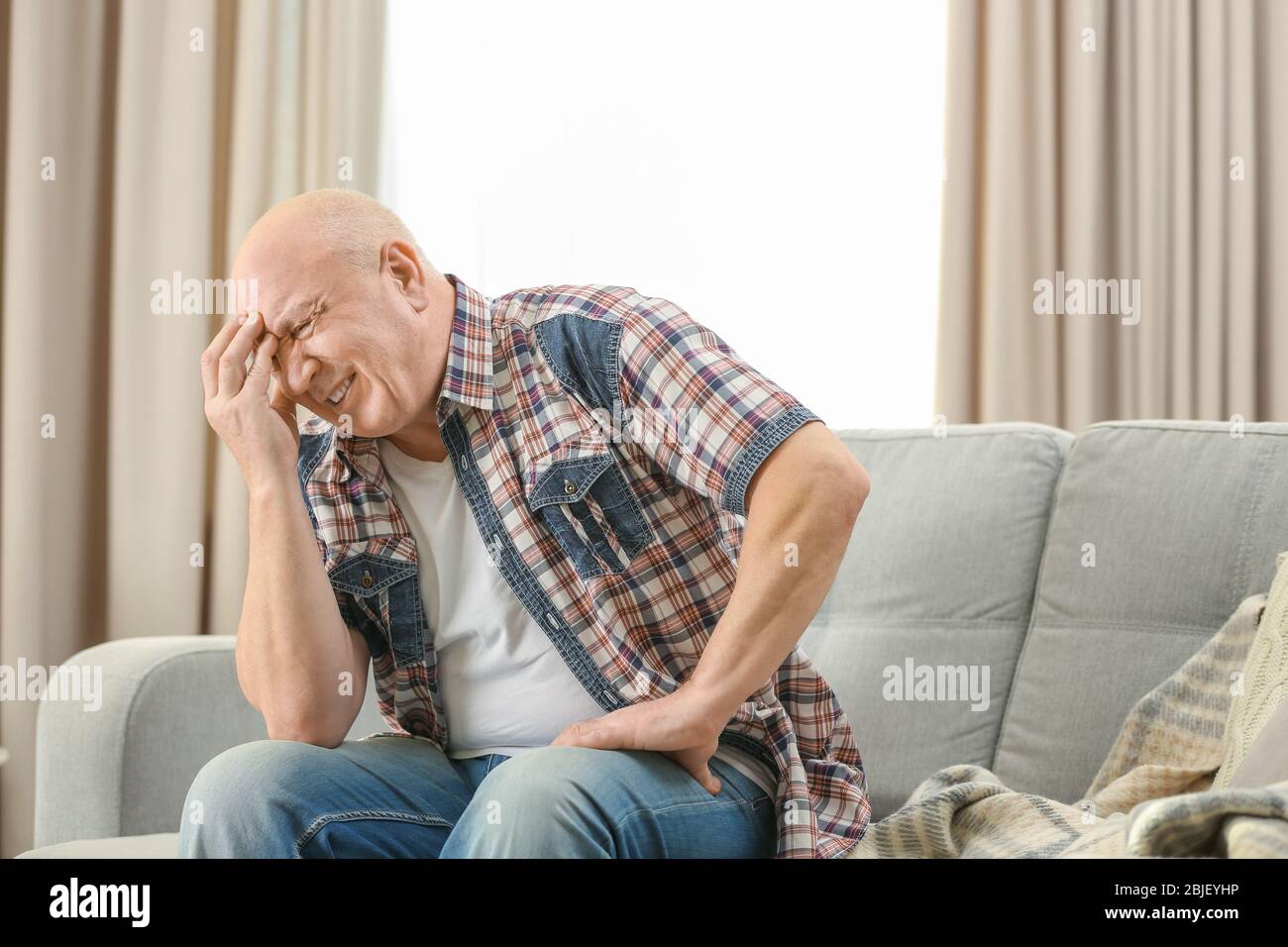 Senior man suffering from headache at home Stock Photo