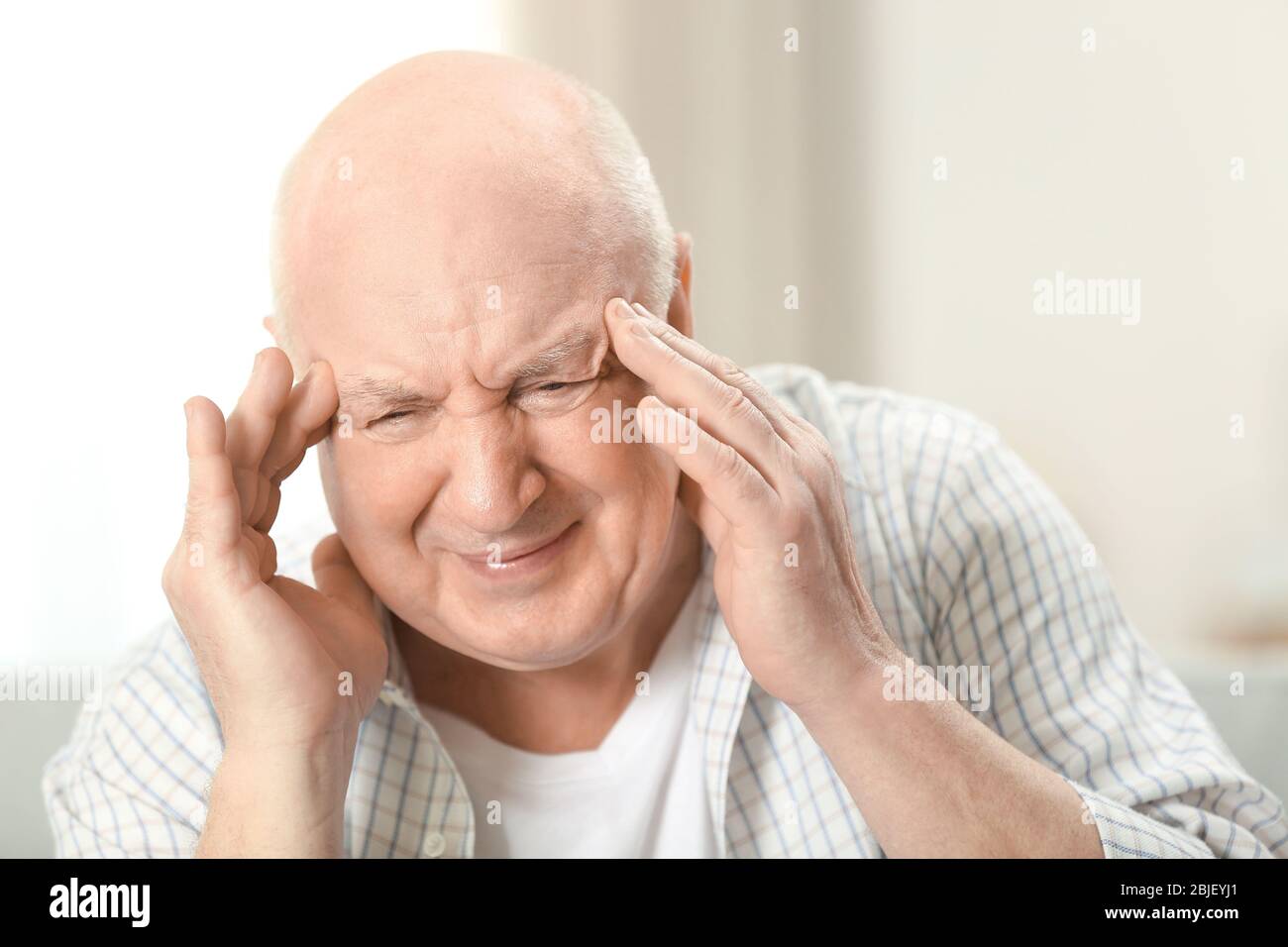 Senior man suffering from headache at home Stock Photo - Alamy