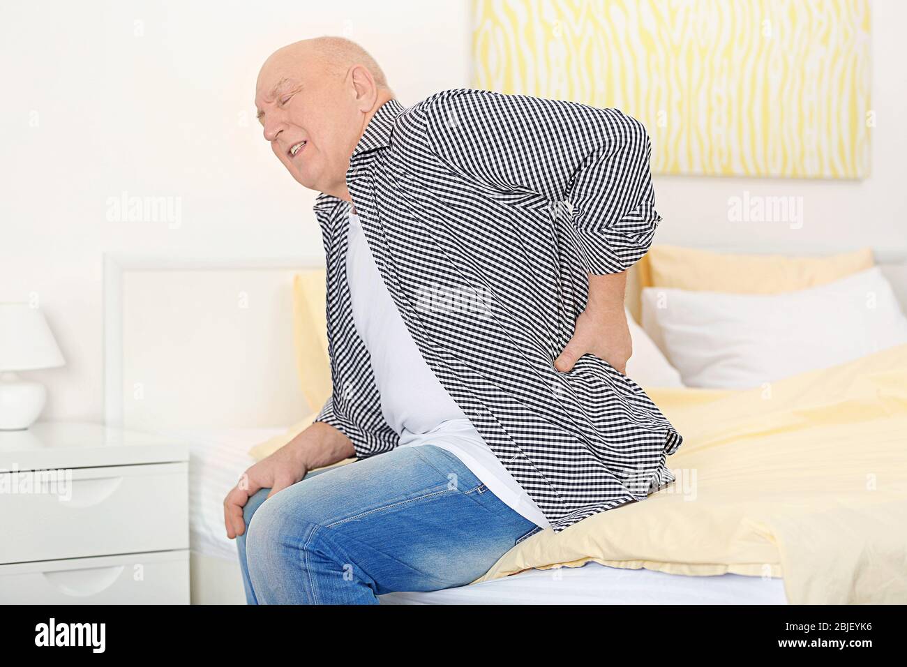Senior man suffering from back pain at home Stock Photo - Alamy