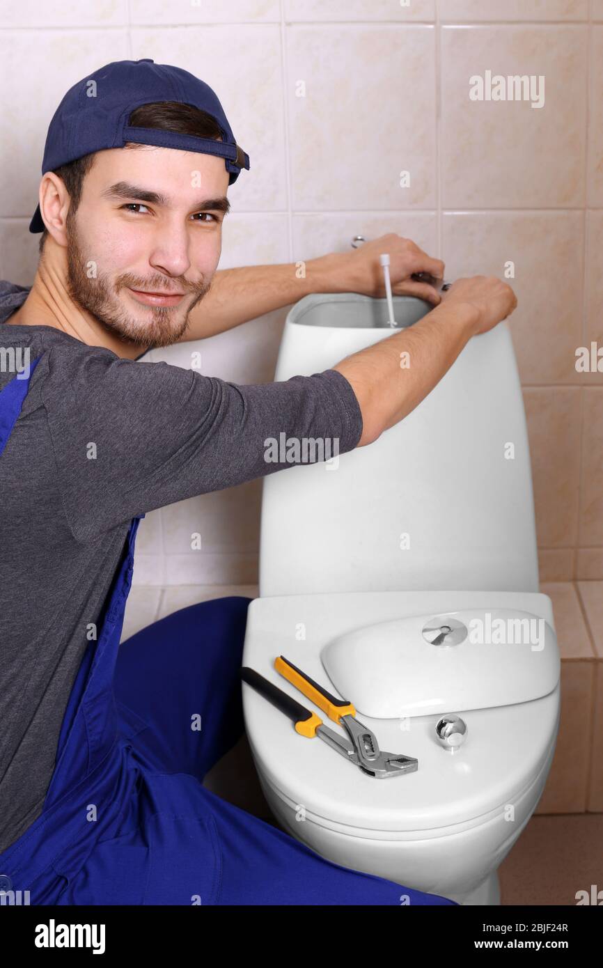 Plumber repairing toilet cistern at water closet Stock Photo Alamy