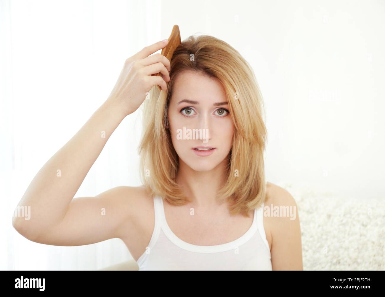 Beautiful young woman brushing hair at home Stock Photo