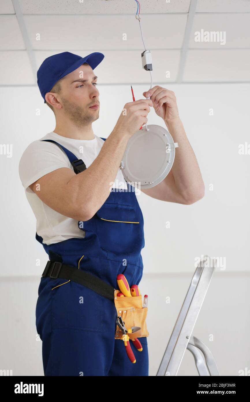 Electrician repairing ceiling light Stock Photo - Alamy