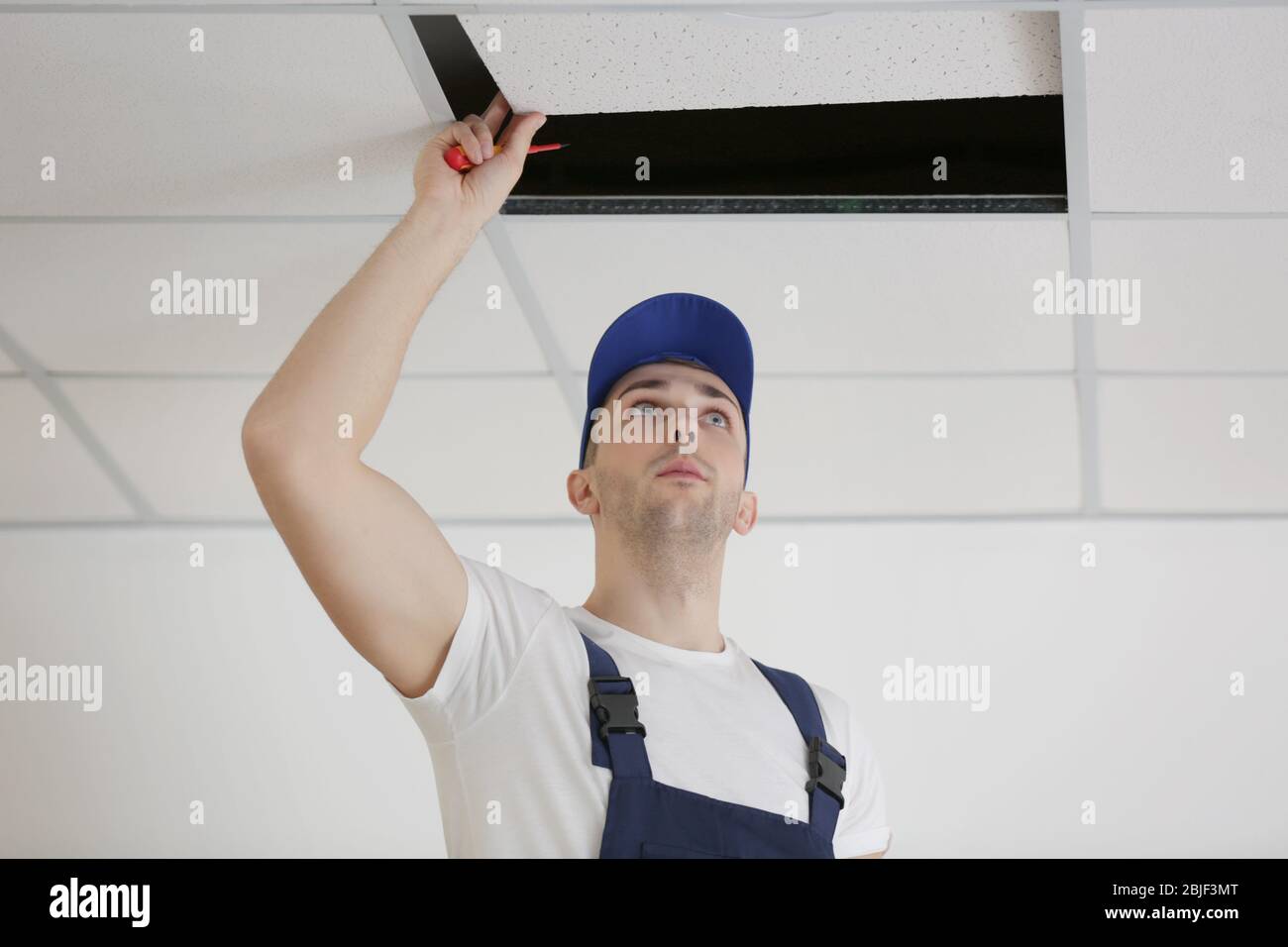 Electrician repairing ceiling light Stock Photo - Alamy