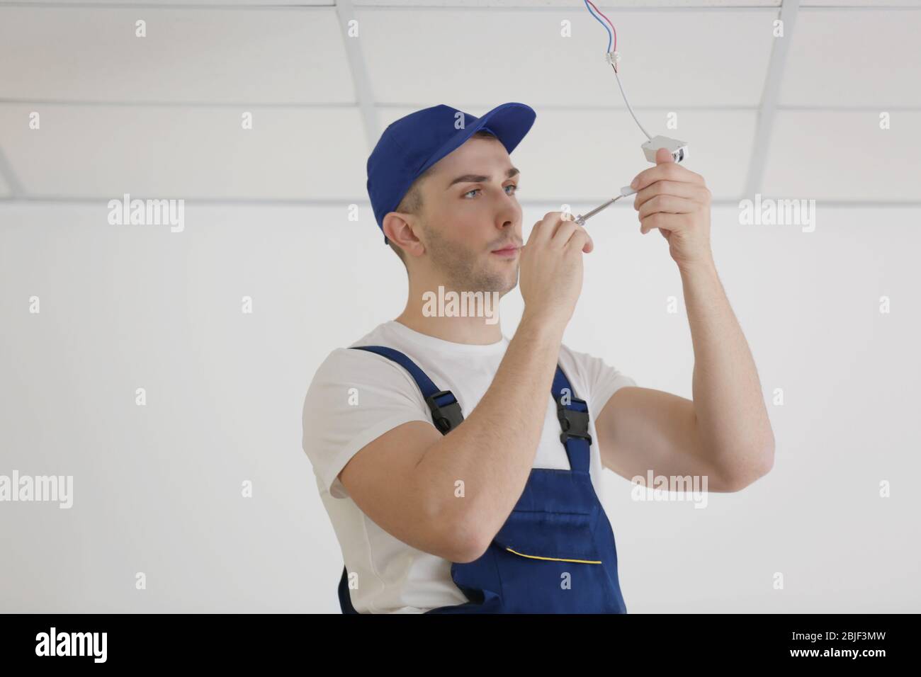 Electrician repairing ceiling light Stock Photo