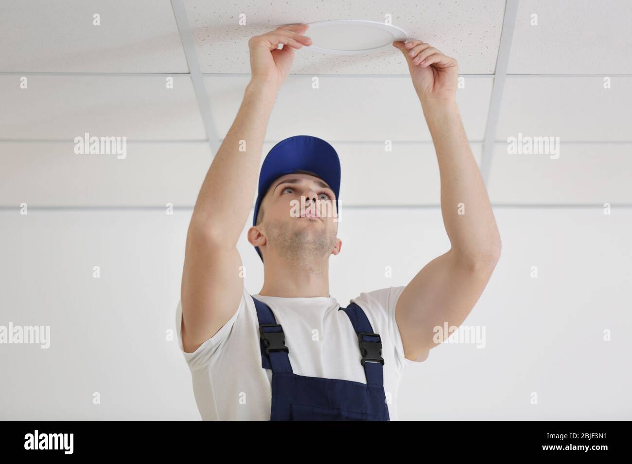Electrician repairing ceiling light Stock Photo - Alamy