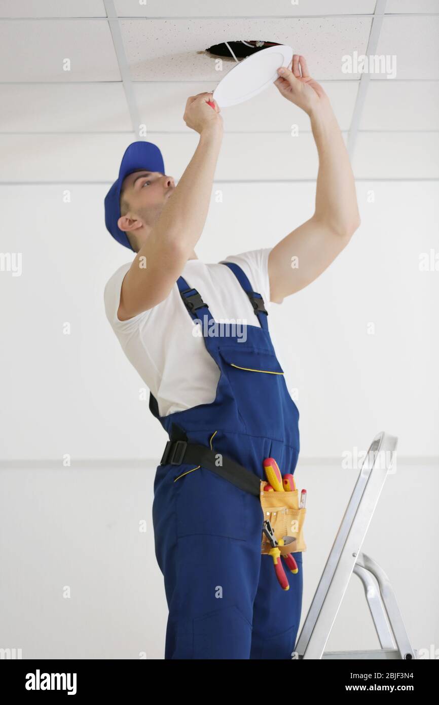 Electrician repairing ceiling light Stock Photo