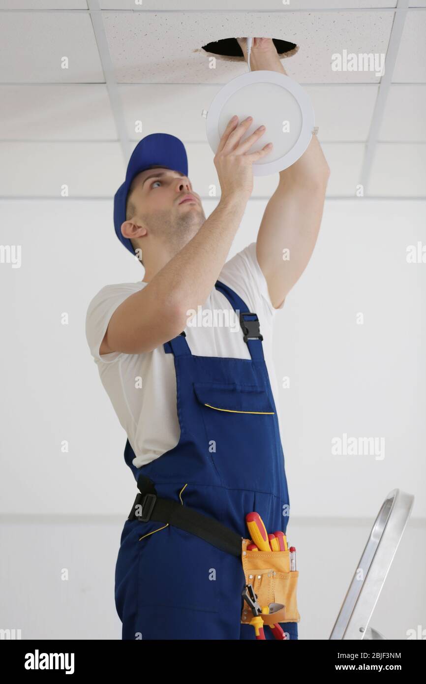 Electrician repairing ceiling light Stock Photo - Alamy