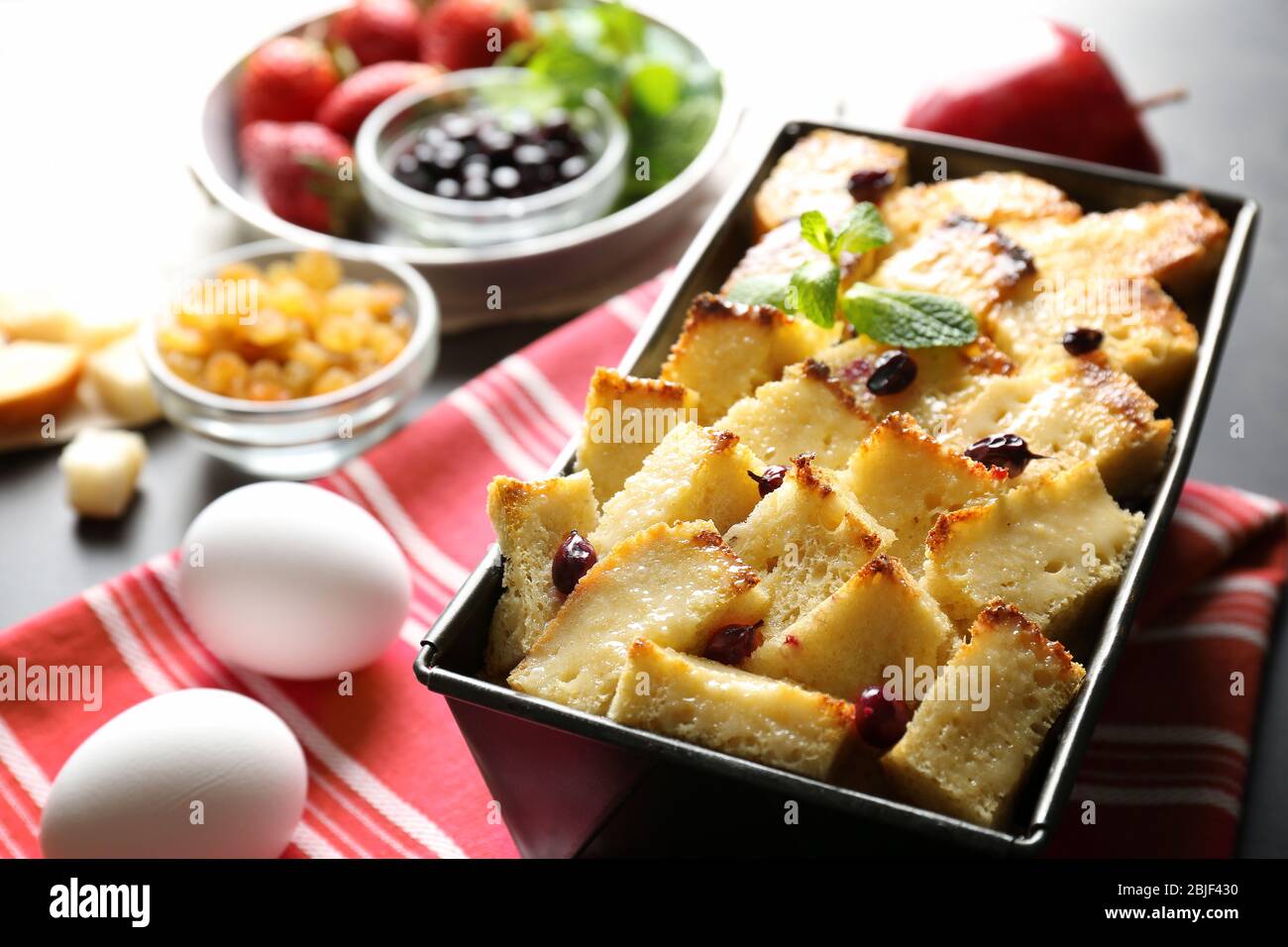 Delicious bread pudding with currant in baking dish on kitchen table Stock Photo