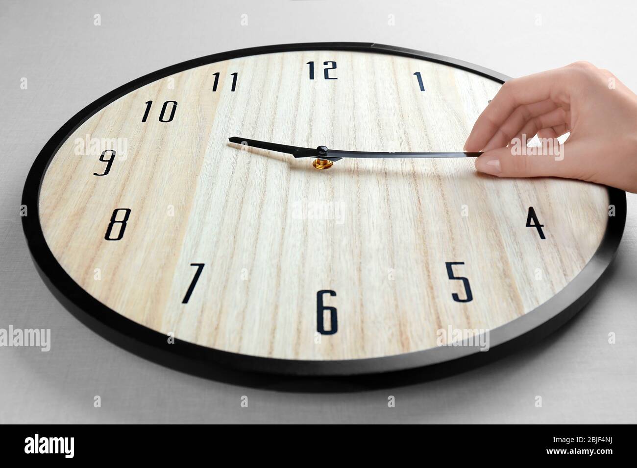 Female hand change time on big wall clock Stock Photo