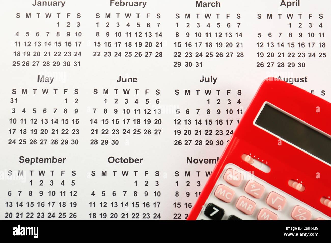 Red calculator on calendar background Stock Photo - Alamy