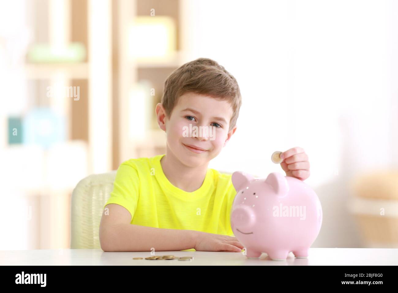 Little boy saving coins in piggy bank at home Stock Photo - Alamy