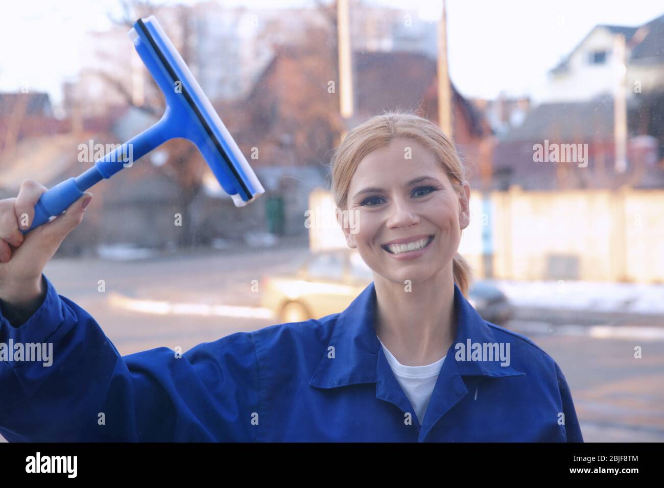 Woman cleaning window with scraper, view through glass Stock Photo - Alamy