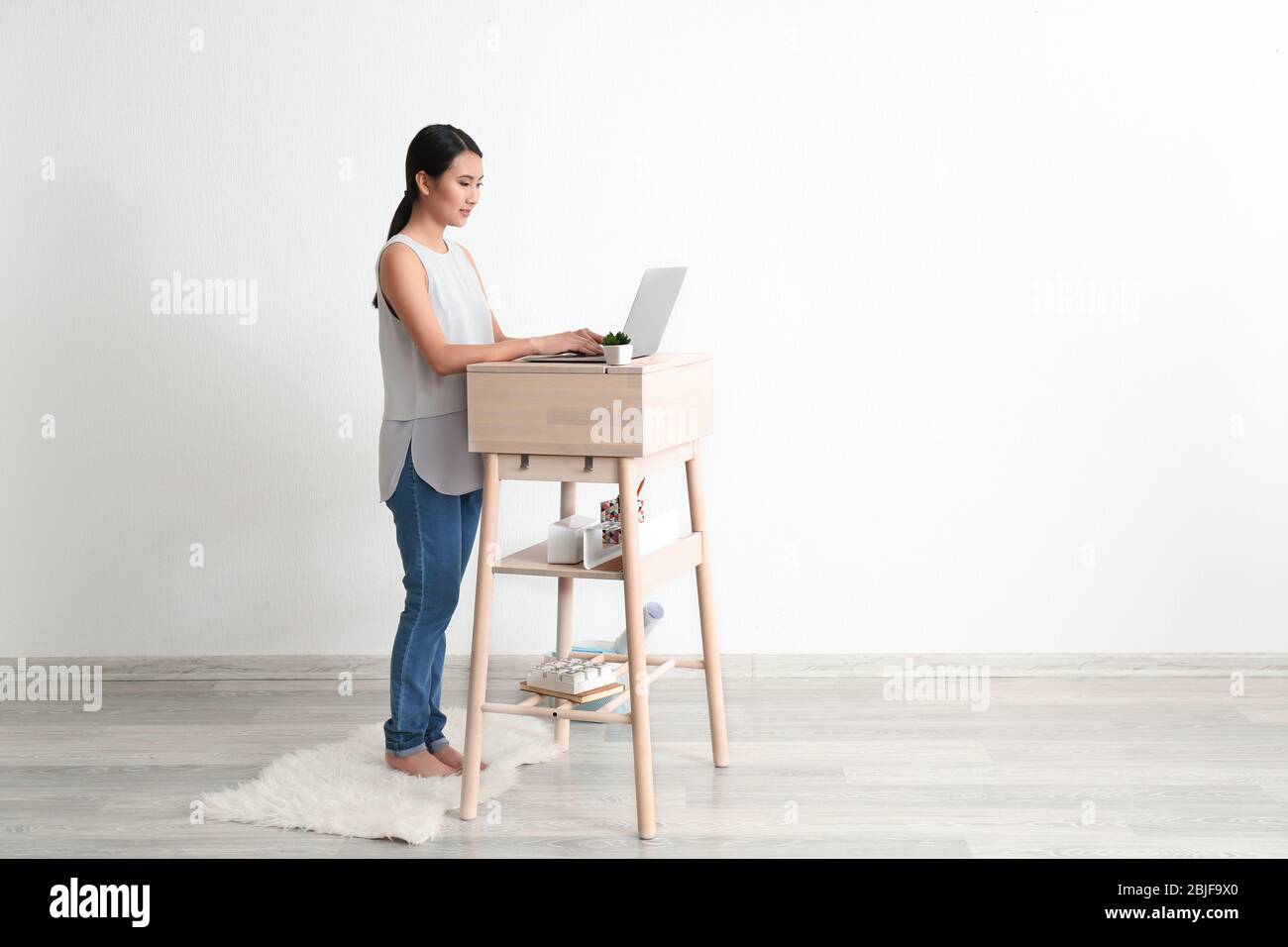 Asian woman typing on laptop at stand-up workplace Stock Photo