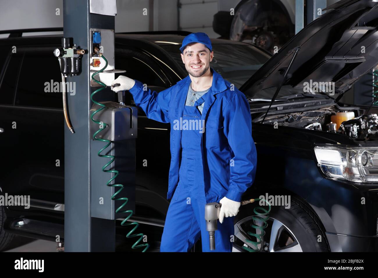 Young mechanic standing near auto lift in car service Stock Photo