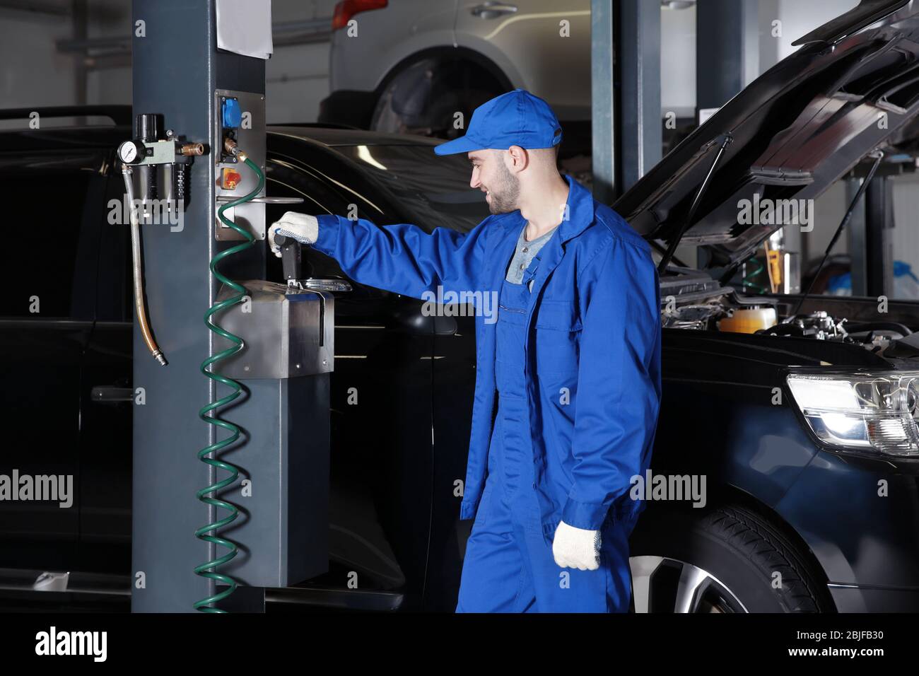 Young mechanic standing near auto lift in car service Stock Photo