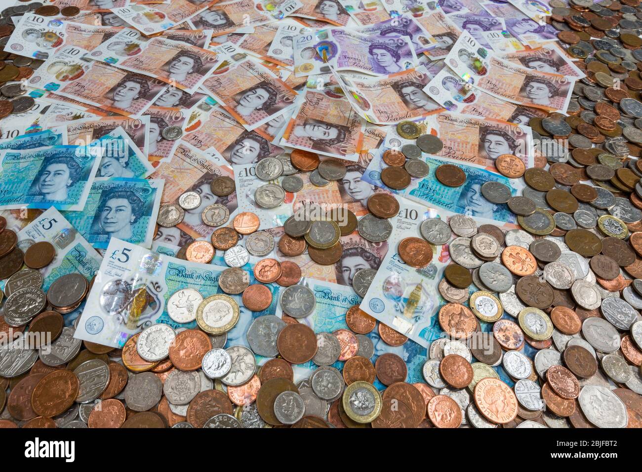 UK sterling  pound notes and coins. New polymer £5, £10 and £20 notes and all coins from 1penny to £2. Stock Photo