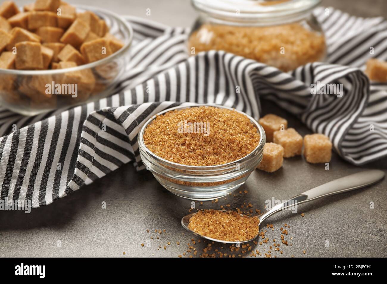 Brown sugar in dishware on gray background Stock Photo