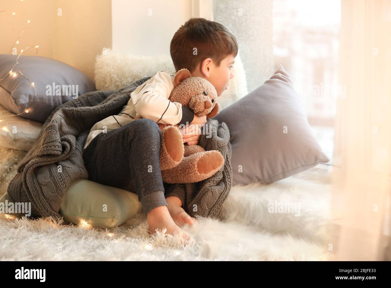 Cute little boy with teddy bear near window at home Stock Photo - Alamy