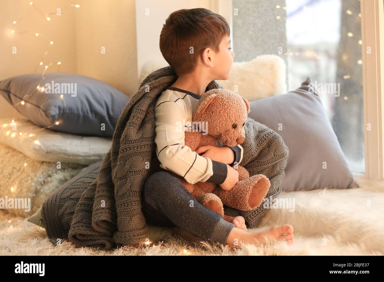 Cute little boy with teddy bear near window at home Stock Photo - Alamy