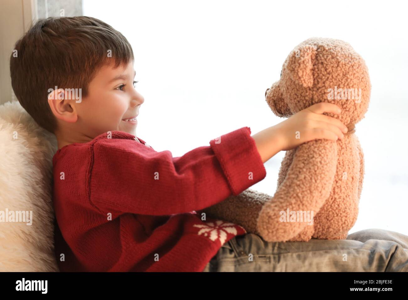 Cute little boy with teddy bear near window at home Stock Photo - Alamy