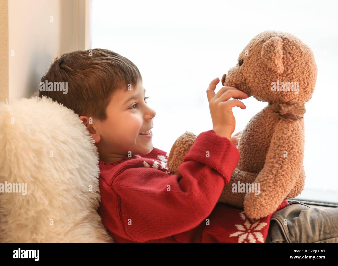 Cute little boy with teddy bear near window at home Stock Photo - Alamy